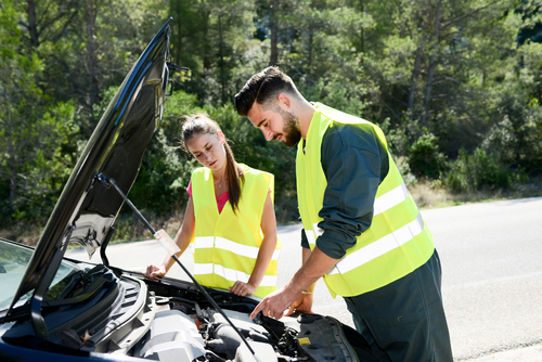 young woman and mechanic assistance on roadside with car breakdown