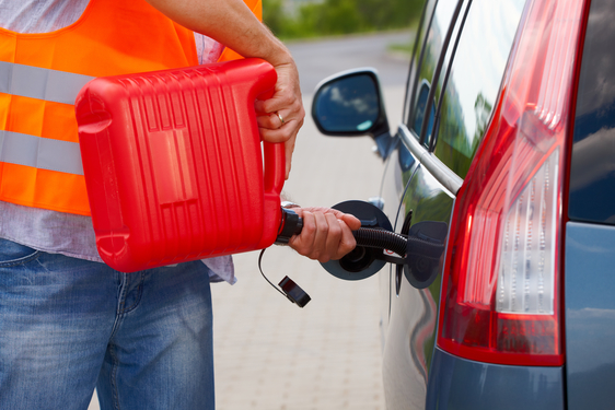 Man pouring fuel into the gas tank of his car from a red gas canister.